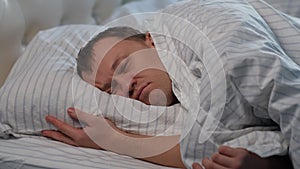 Young man lies awake in his bed, suffering from insomnia