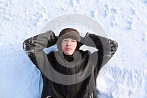 Young man lies on back on snow