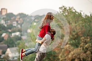 Young man lifted up girl in his hands and they laugh cheerfully