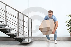 Young man lifting carton box indoors