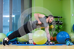 Young man lifting dumbbell at the fitness center