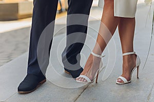 Young man lifting his bride up outdoors, close-up of lower part of the bodies.