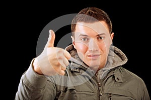 Young man lifts thumb upwards