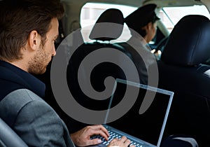 Young man in limousine using laptop computer