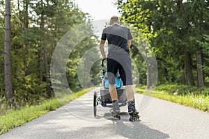 Young man in line skating outdoors with baby stroller