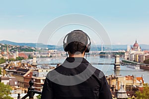 Young man listening music back view with Budapest