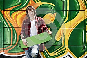Young man listening music near a graffiti wall