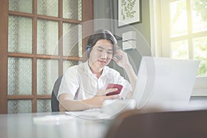 Young man listening music using mobilephone and headphone in coffee shop,feeling relax