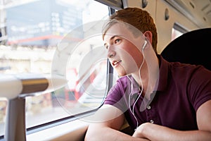 Young Man Listening To Music On Train Journey