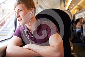 Young Man Listening To Music On Train Journey