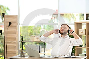 Young man listening to music while working with laptop