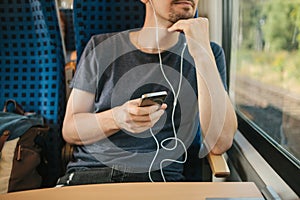 A young man listens to a music or podcast while traveling in a train