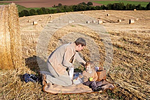 Young man and little boy making picnic on hay field