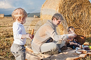 Young man and little boy making picnic on hay field