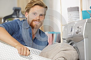 young man loads laundry into washing-machine