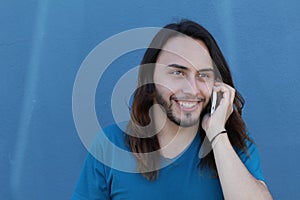 Young man with long hair and beard enjoying talking on phone