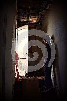 Young Man look out the door of an old building