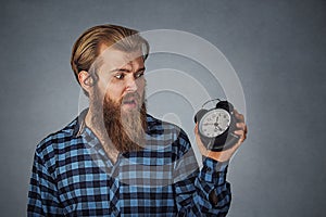 Young man looking at alarm clock with fear being late