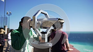Young man looking through binoculars at observation deck and leaving, tourism