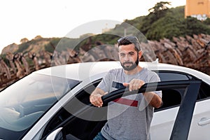 Young man looking at camera from the door of car