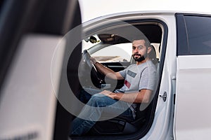 Young man looking at camera sitting in his car