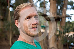 Young man looking into camera and standing in the forest