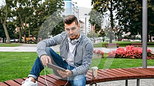 Young man looking camera using tablet outdoors