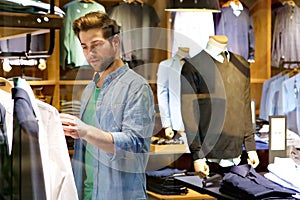 Young man looking at clothes to buy at shop