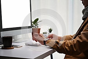 Young man looking at computer screen and working on project in modern office.