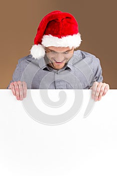 Young man looking down on blank panel on brown background.