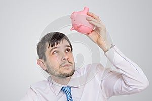 Young man is looking in empty piggy money bank