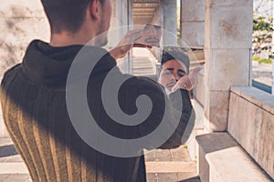 Young man looking at himself in a broken mirror