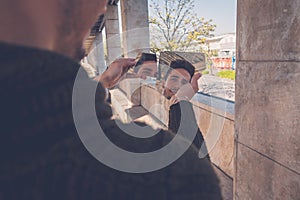 Young man looking at himself in a broken mirror