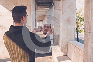 Young man looking at himself in a broken mirror