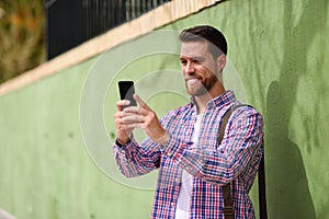 Young man looking at his smart phone in urban background. Lifestyle concept.