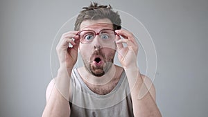 Young man looking through huge glasses in shock with surprise expression.