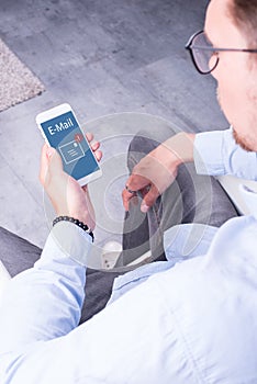 Young man is looking at incoming e-mail on his smartphone