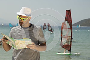 Young man looking at the map on the beach.