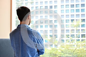 Young man looking out of the window in the room