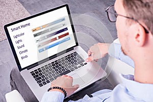 Young man is looking an smart home app on his laptop