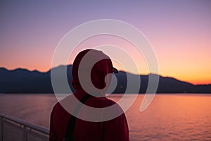 Young man is looking at the sunrise or sunset at the sea. Rear view of a man standing at the seaside during sunrise