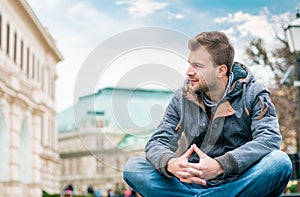 Young man looking to side and sitting. Guy wearing warmly or winter jacket