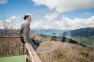 Young man looking at the view from a top of mountain.