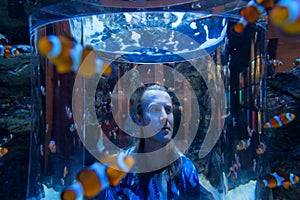Young man looks at clown fish in a huge tank