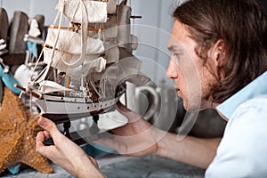 Young man looks at model of sailing ship in vintage interior