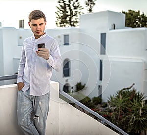 Young man looks at the a smartphone, summer outside, place for text, phone outdoor