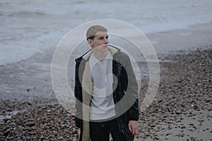 The young man looks to the side with a thoughtful look to the side against the background of the sea