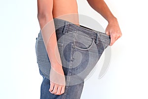 Young man in loose jeans on white background. Weight loss concept.