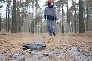 Young man loses his purse with euro money bills on Russian autumn fir wood path. Carelessness and losing wallet concept