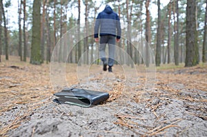 Young man loses his purse with euro money bills on Russian autumn fir wood path. Carelessness and losing wallet concept